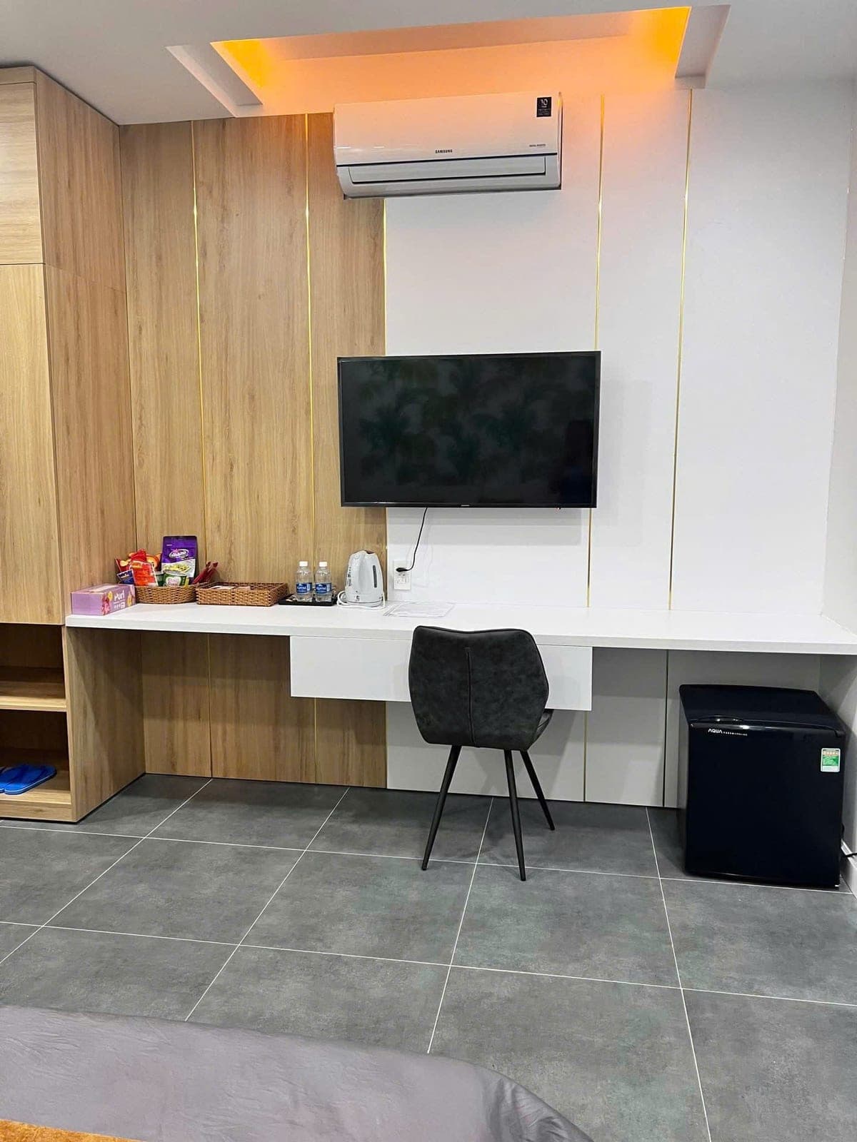 Bàn làm việc, tivi, tủ lạnh mini và ấm đun nước trong phòng