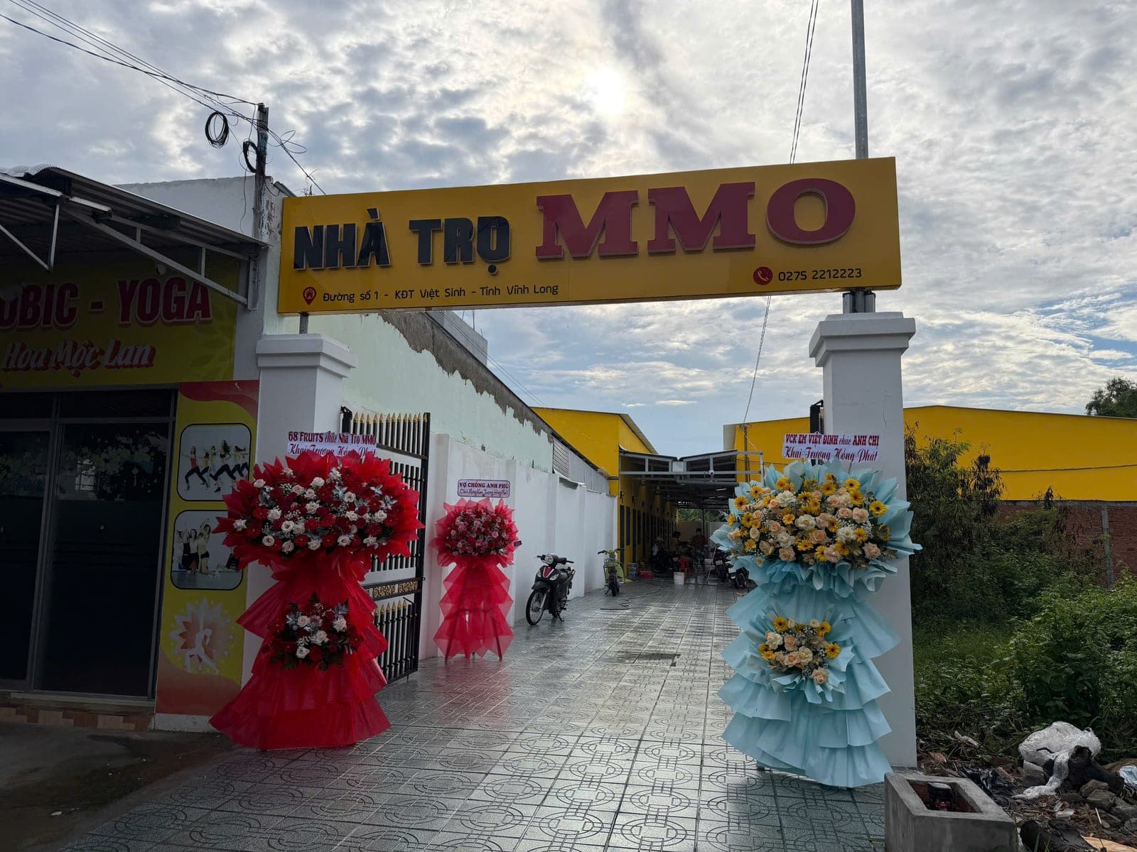 Cổng vào Nhà Trọ MMO với biển hiệu vàng bên đường